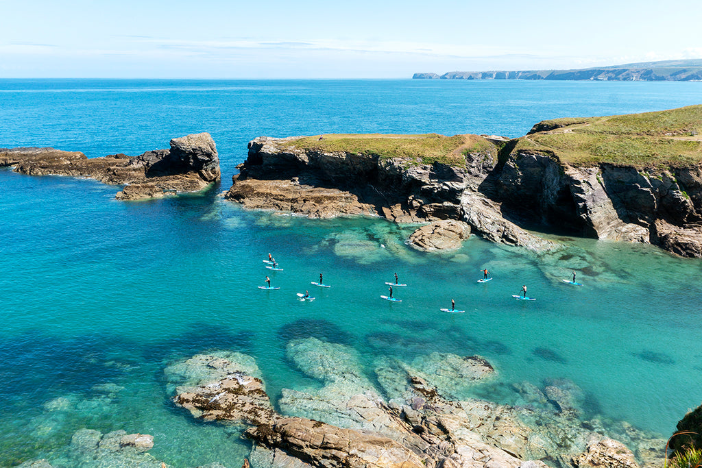 stunning blue sea and cornish coastline dotted with paddle boarders