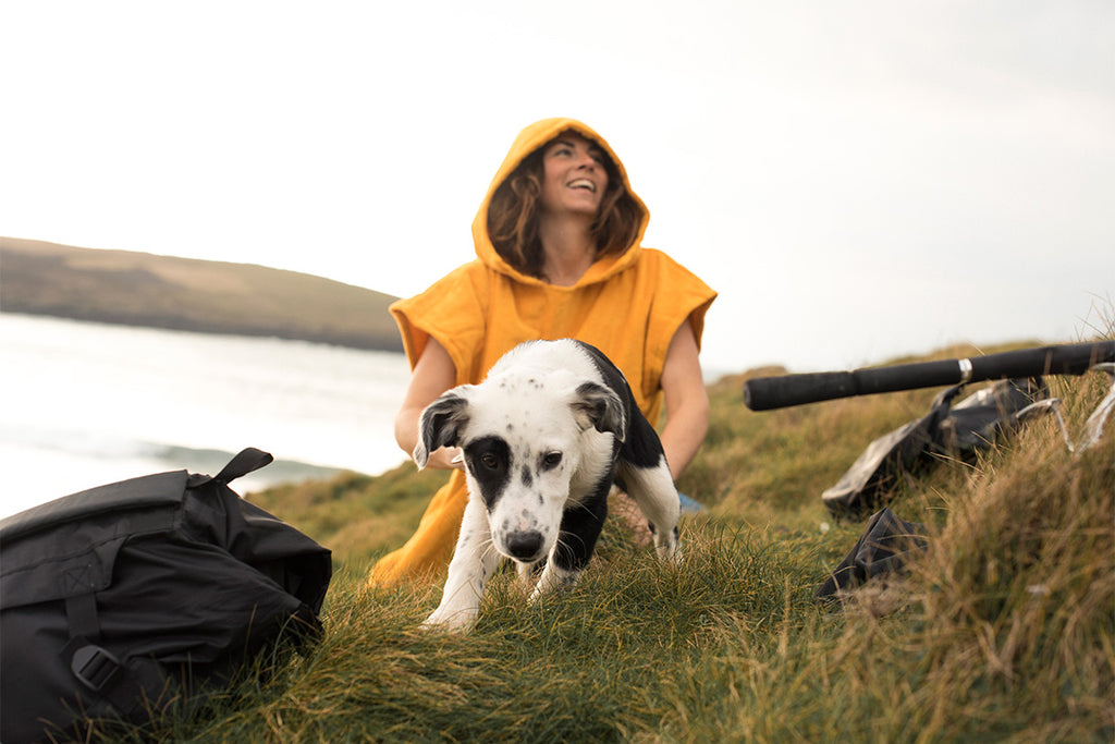 black and white puppy with girl in yellow towel on clifftop